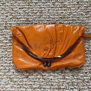 Hobo International fold top clutch in orange, kiss clasp and hand loop in back